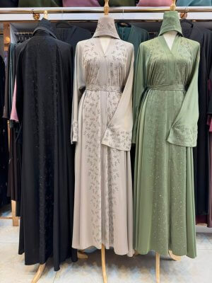 Embroidered Dubai abaya available in sage green, sand beige, and black with elegant botanical detailing.